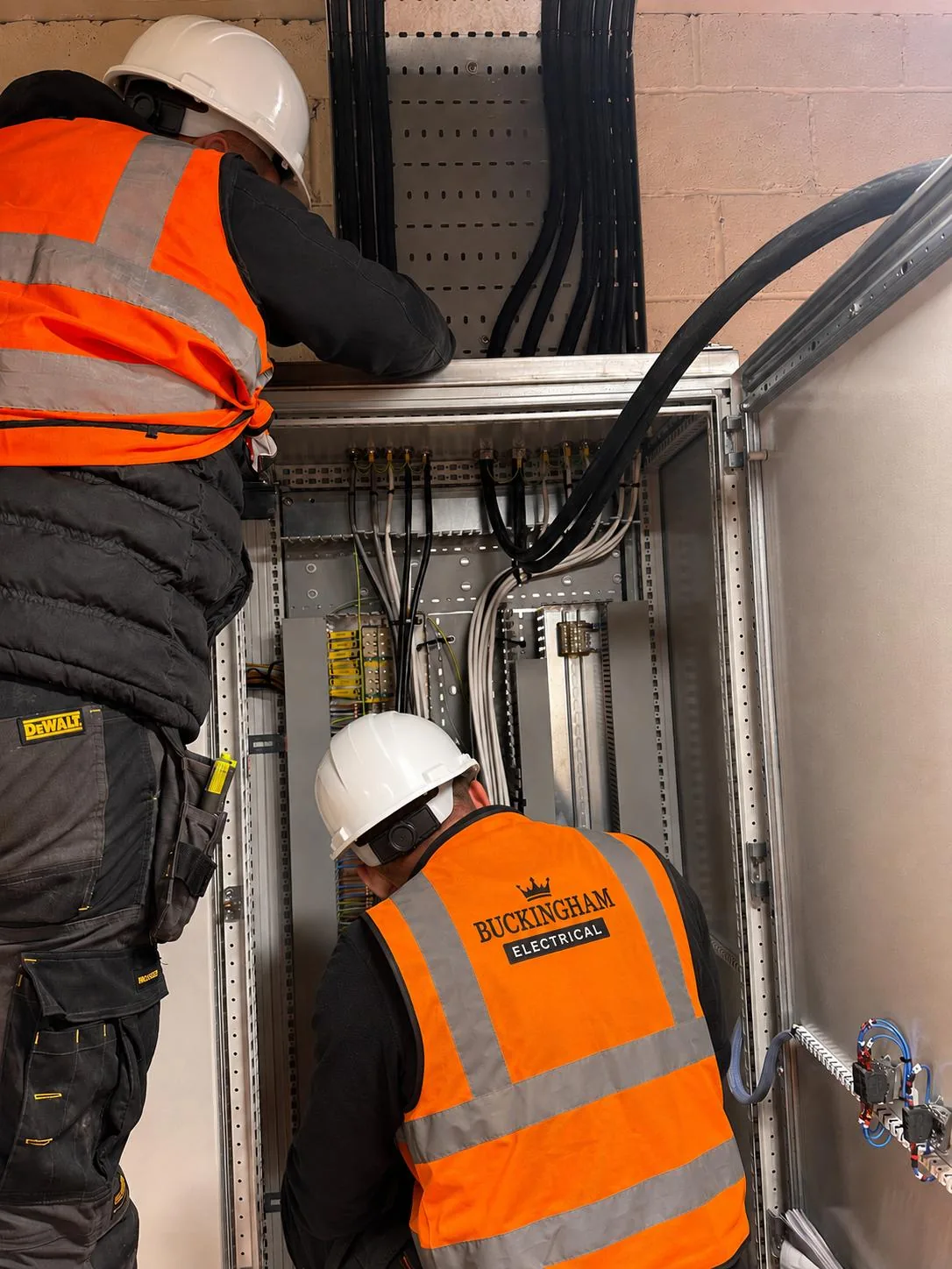 Two Buckingham Electrical engineers wiring a control panel on site