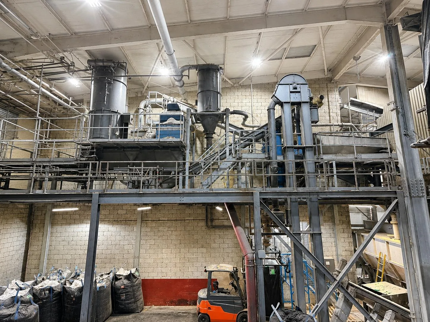 Automated grinding plant installed across mezzanine and ground floor levels at an industrial processing facility