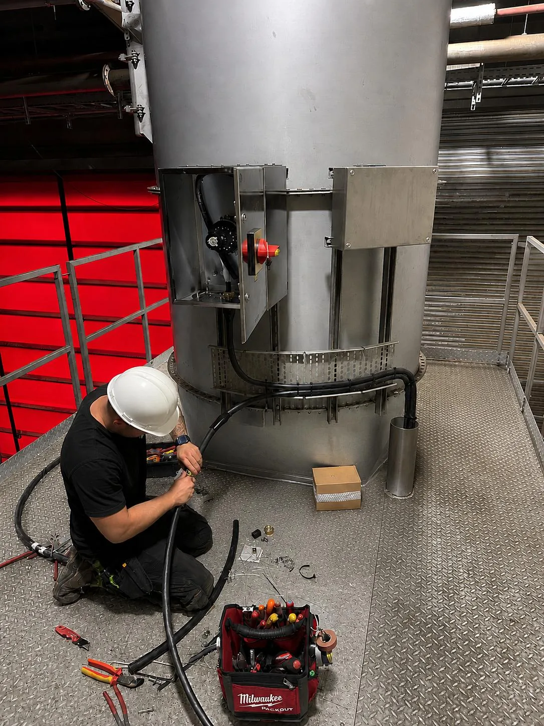 Engineer terminating cabling at the base of a process vessel during installation